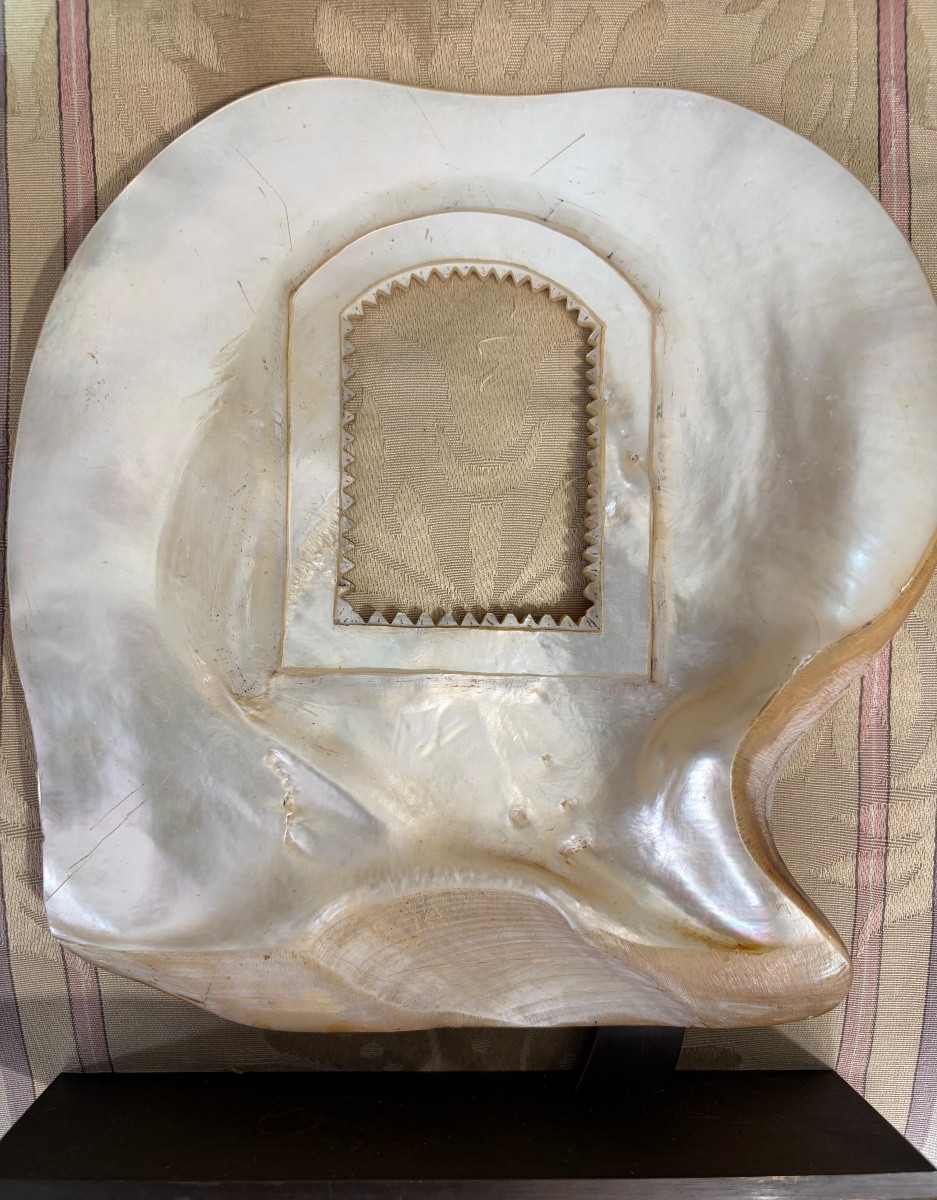 Grand coquillage de nacre, repercé d’une petite fenêtre aux bords dentelés, cadre à photos. 