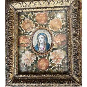 Portrait de la Vierge, entouré de marqueterie de paille, sous forme de fleurs. Cadre Louis XIII