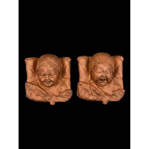 Paire de bas-relief en terre cuite - Bébés au béguin (le rire et les larmes) 