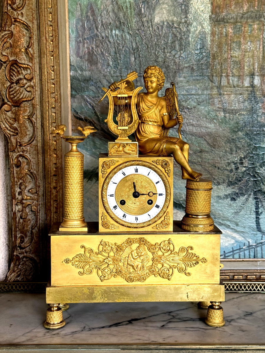 PENDULE ÉPOQUE EMPIRE EN BRONZE DORÉ A DECOR D'EROS JOUANT DE LA HARPE