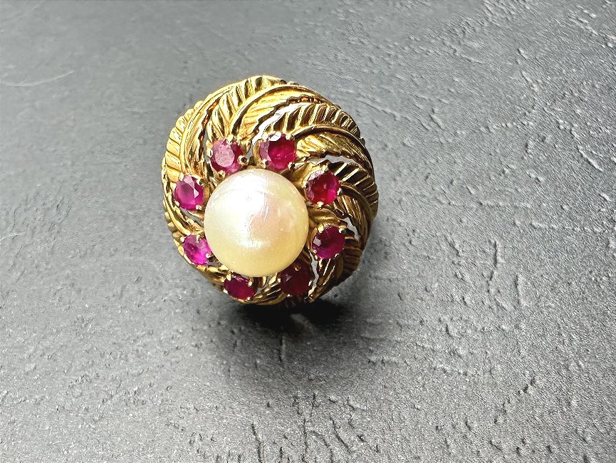 A Yellow Gold Ring Featuring A Cultured Pearl Set In The Center, Surrounded By Treated Rubies.