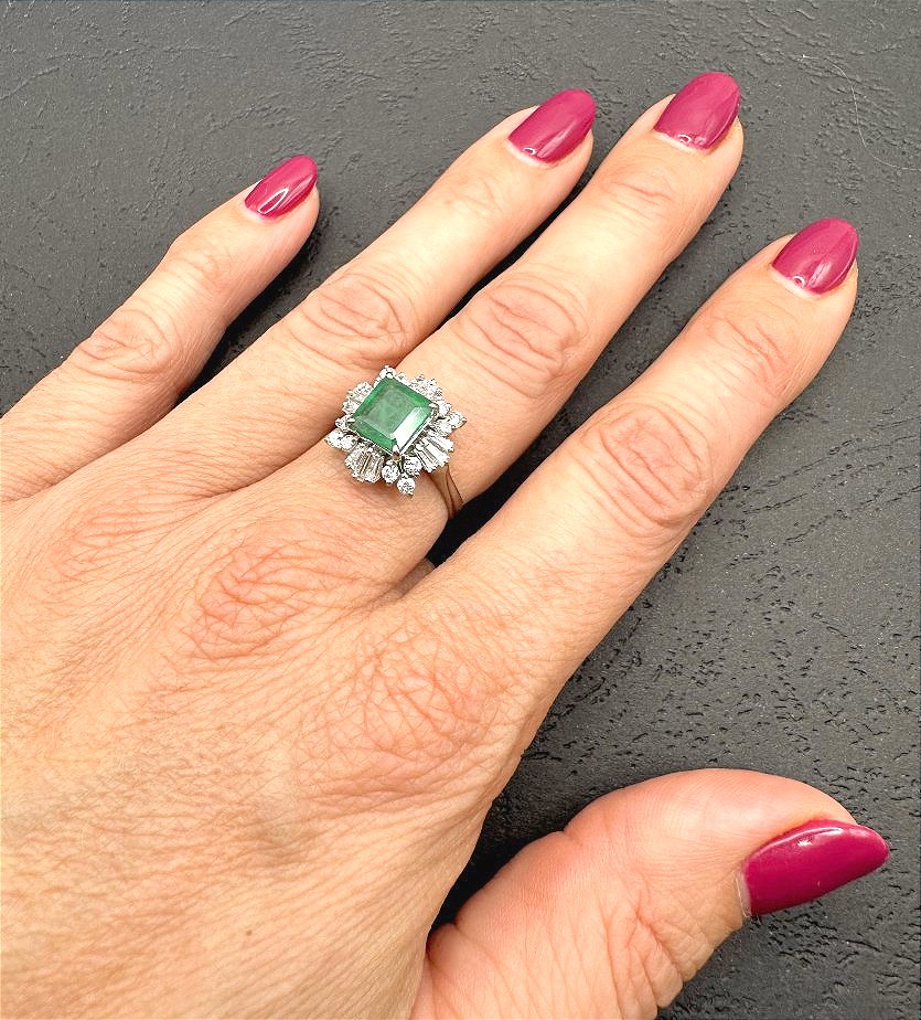 White Gold Ring Set With A Center Emerald And A Diamond Border