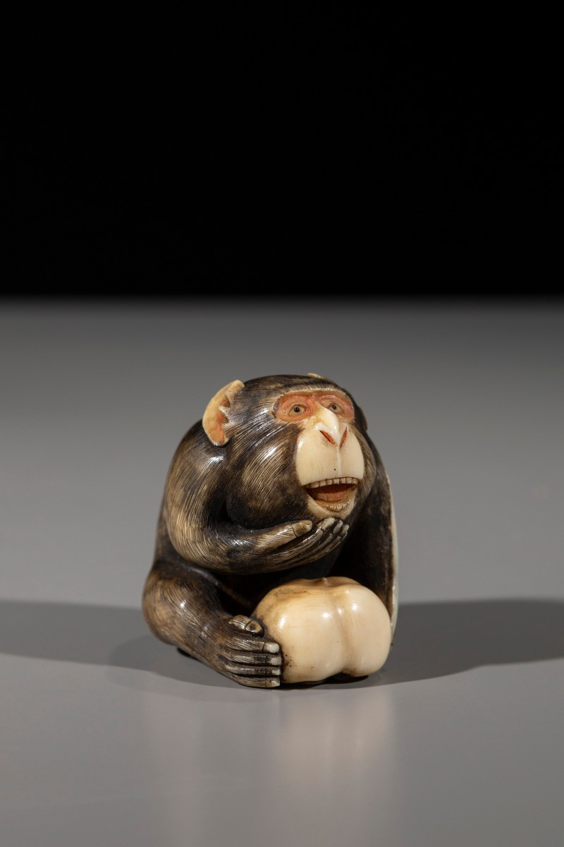 An Ivory Netsuke Depicting A Monkey With Fruit