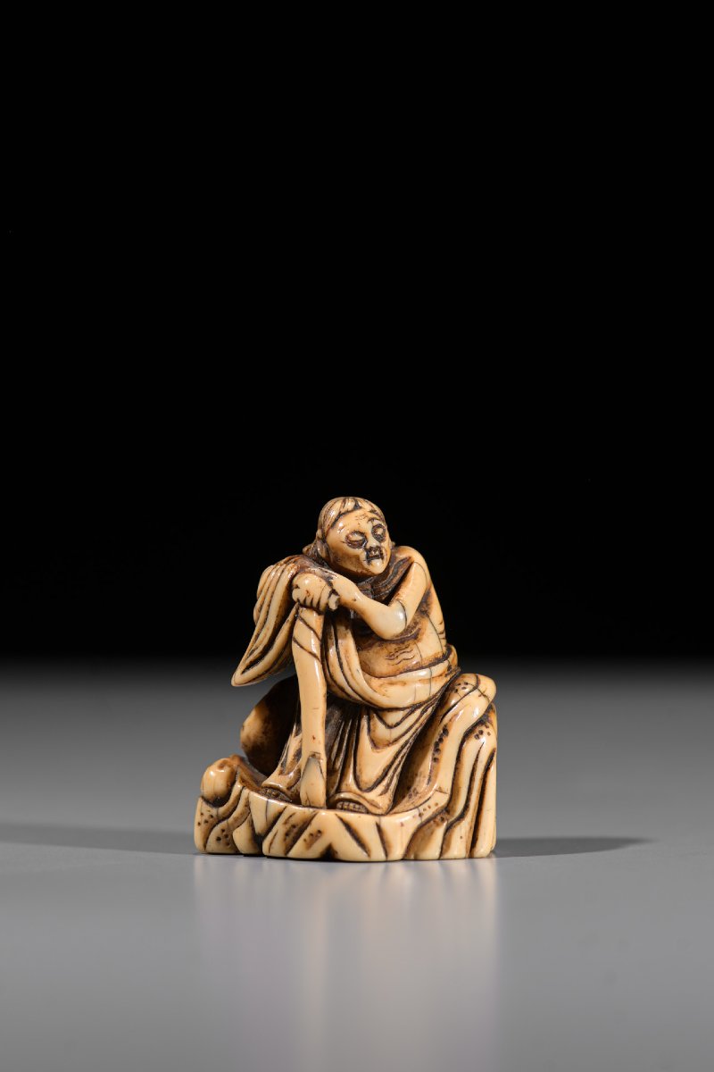 Netsuke en ivoire représentant un Rakan assis sur un rocher