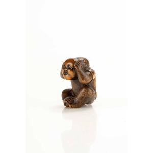 A Boxwood Netsuke Depicting A Monkey With An Okame Mask