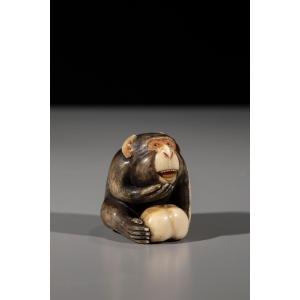 An Ivory Netsuke Depicting A Monkey With Fruit