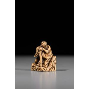 Netsuke en ivoire représentant un Rakan assis sur un rocher