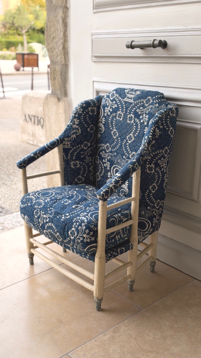 Bergère provençale du XVIIIe siècle en bois peint, garnie d’un ancien tissu piqué bleu de Nîmes