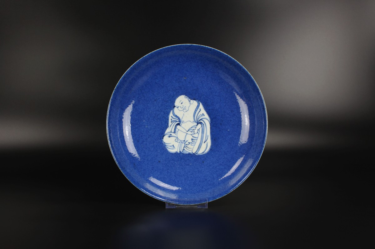 Plat Budai en porcelaine chinoise à fond bleu poudré et à décor bleu et blanc, dynastie Qing