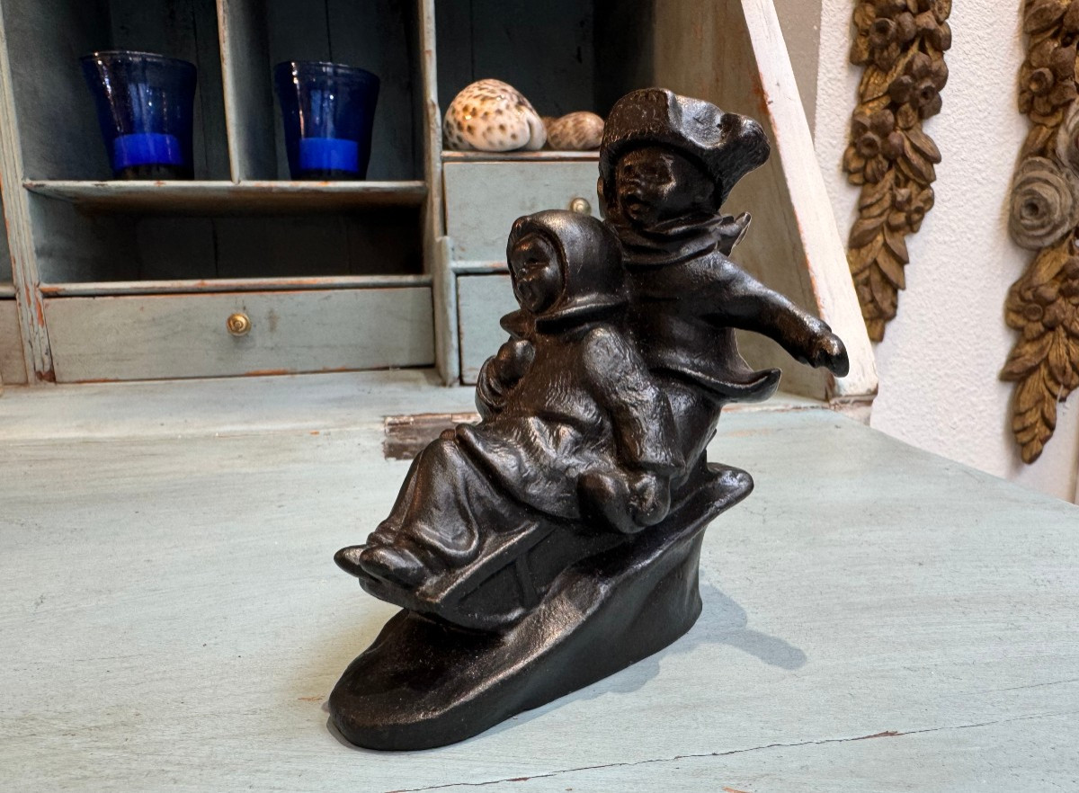 Ancienne et petite sculpture en fonte enfants sur une luge vers 1920