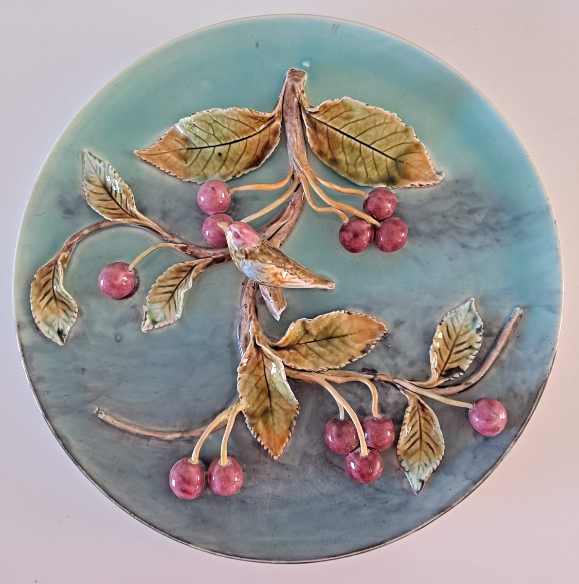 Plat décoratif en Barbotine à décor d'une banche de cerises et d'un oiseau