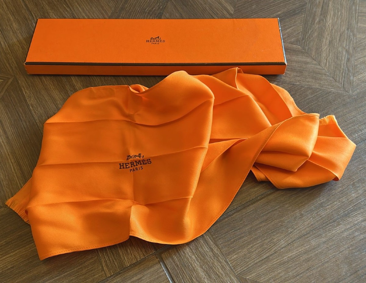 Cravate-foulard Hermès en pure soie, dans la couleur emblématique de la maison française. 