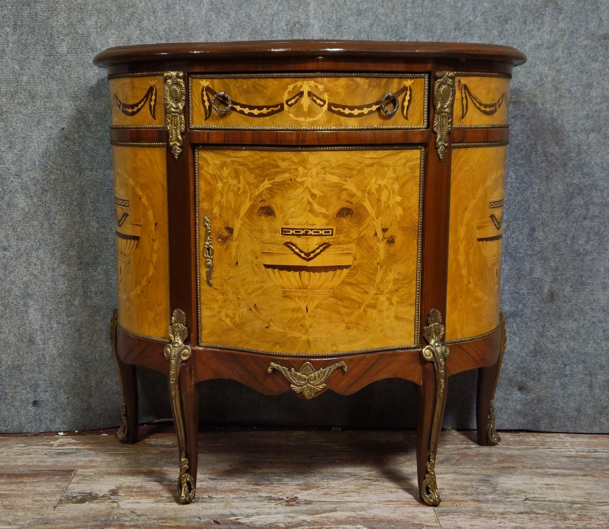 Commode demi-lune de style Louis XV en marqueterie et décors de bronze.