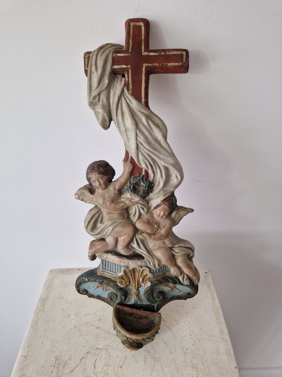 Bénitier religieux ancien sculpté et polychrome, orné de putti (anges) et d'une croix.