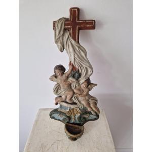 Bénitier religieux ancien sculpté et polychrome, orné de putti (anges) et d'une croix.
