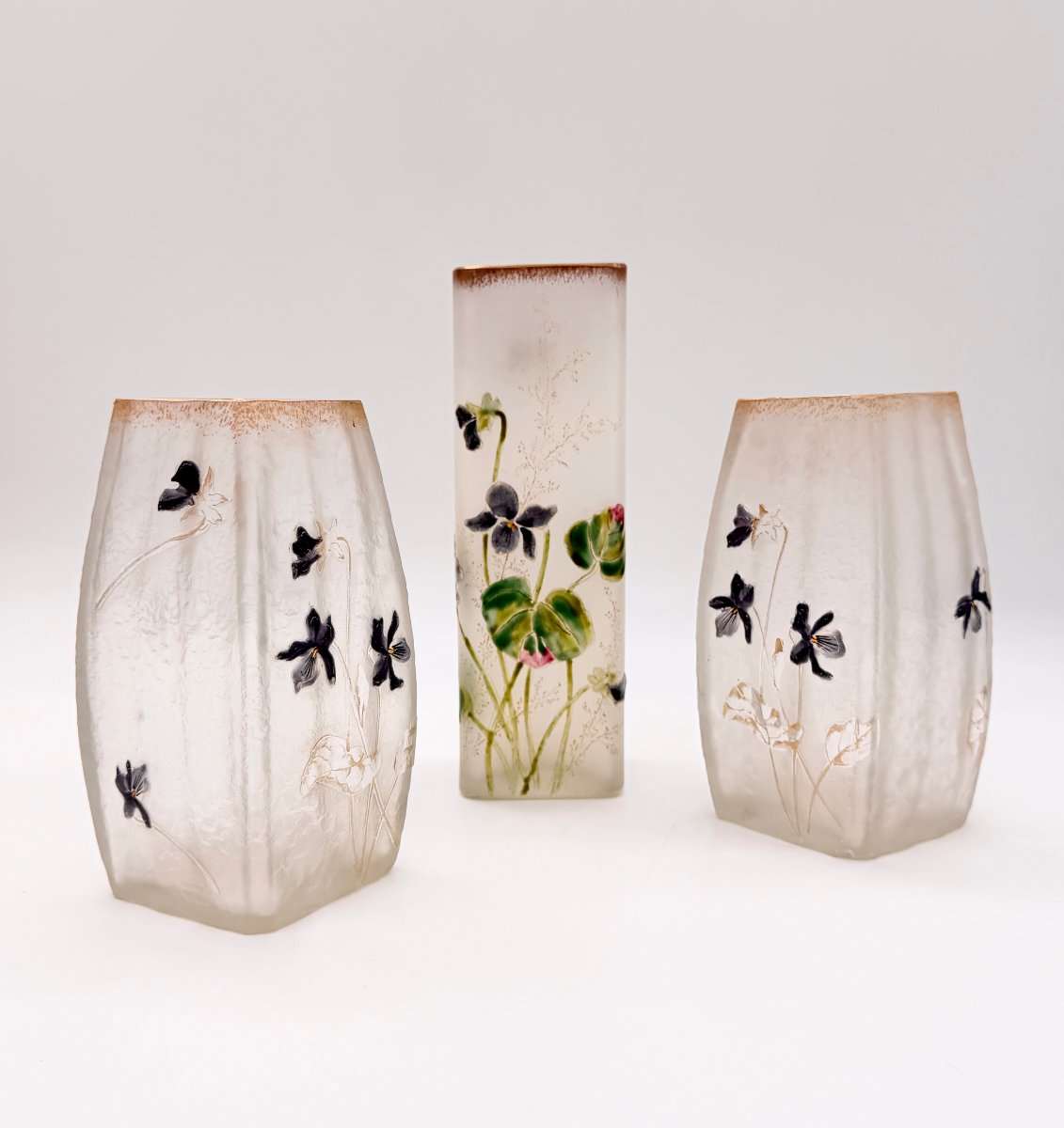 GARNITURE DE DEUX VASES MEPLAT ET UN VASE CYLINDRIQUE ART NOUVEAU À DÉCOR DE VIOLETTES, DAUM 
