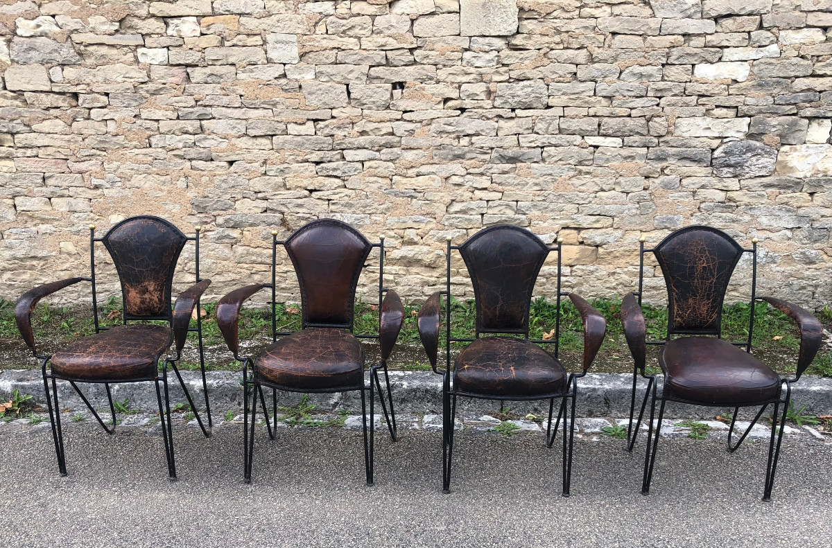 Suite de quatre fauteuils en fer, laiton et cuir par jacques adnet.
