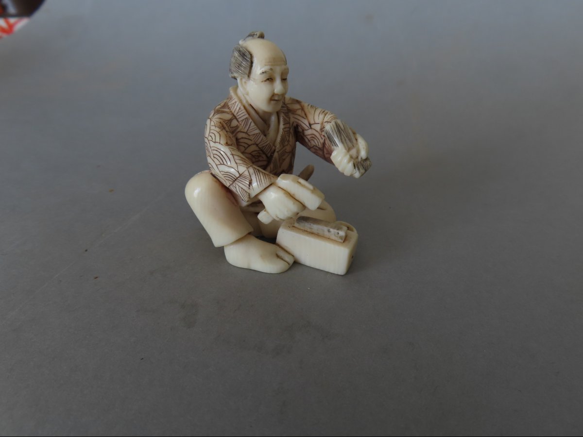 Netsuke en ivoire. Scène de rue, artisan au marteau. Japon époque Taisho (1912-1928 )