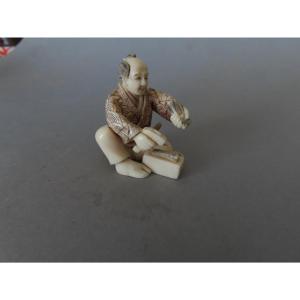 Netsuke en ivoire. Scène de rue, artisan au marteau. Japon époque Taisho (1912-1928 )