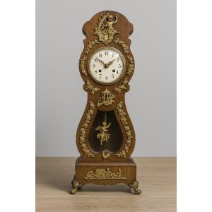 Horloge de maitrise en bois teinté, ornée d’une iconographie d’amours en bronze doré