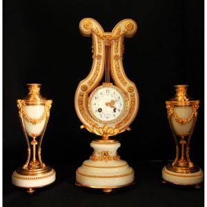 Pendule de cheminée de style lyre accompagnée de deux candélabres assortis.