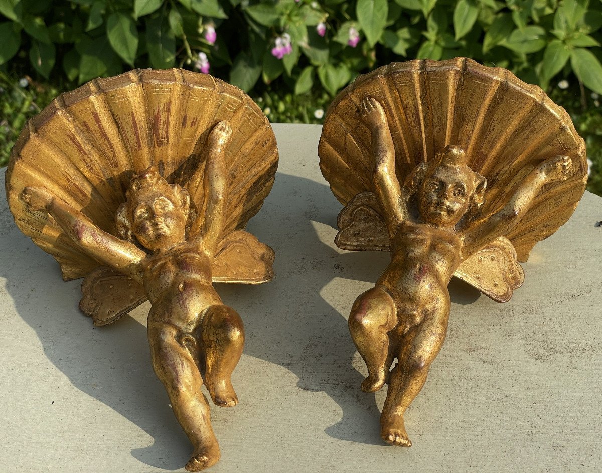 Consoles en bois doré, paire d’angelots, anges et coquille, appliques