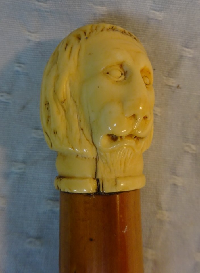 Canne du XVIIIe siècle à pommeau en os figurant une tête de lion aux traits humanisés.
