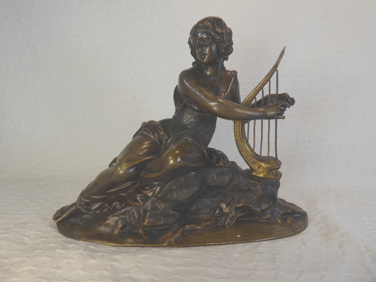 Une sculpture en bronze du XIXe siècle représentant une jeune femme jouant de la harpe.